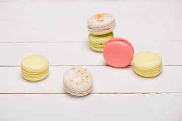 Group of beautiful colorful macarons on white wooden table. Sweets background