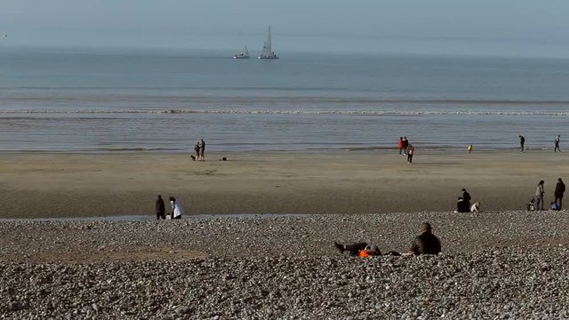 People relaxing on the beach and sailing yachts in Dieppe bay, France. Vacation, luxury lifestyle and wealth concept