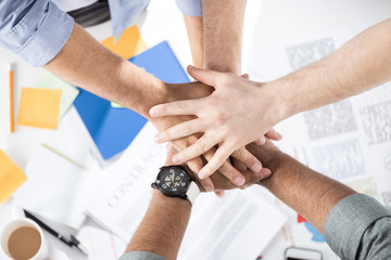 Naklejka premium Close-up partial view of businessmen stacking hands while working on project together, business teamwork concept