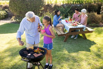 Grandfather and granddaughter doing a barbecue 