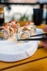 Hand taking sushi roll with chopsticks