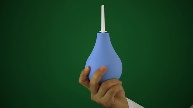 Doctor is holding an enema. An enema in the doctor's hand.