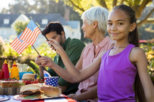 Girl holding American flag near the picnic table