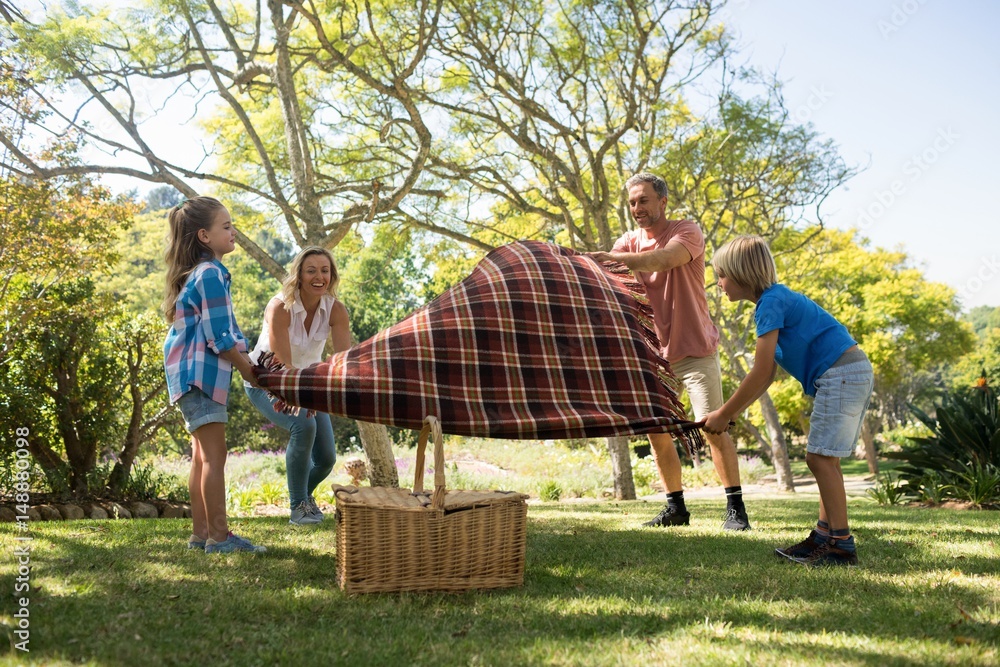 Wall mural family spreading the picnic blanket