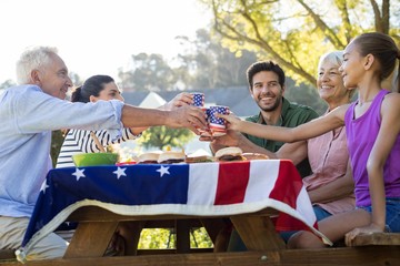 Happy family toasting the cups while having meal in the park