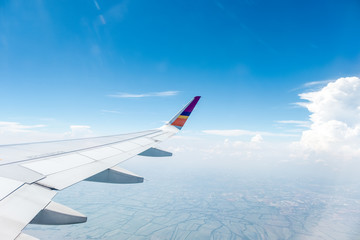 Fototapeta premium Wing of an airplane flying above Clouds