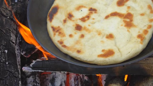 Pita on frying pan on bonfire. Natural healthy food concept. Slow motion.