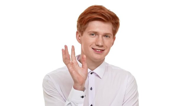 Young handsome Caucasian ginger man calmly standing on white background and slowly waving hand in slowmotion