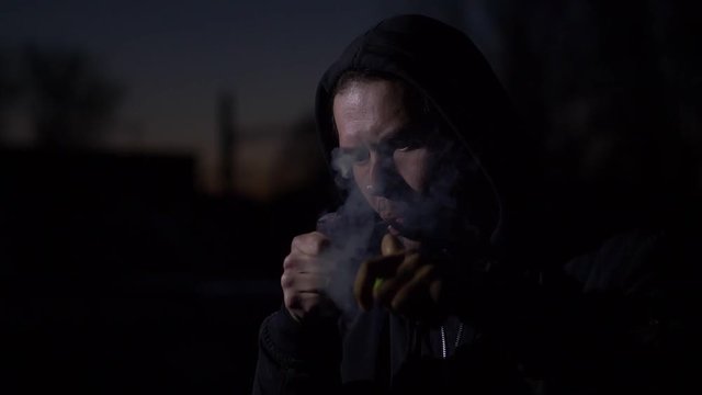 Smoking man in the dark. Slow motion.