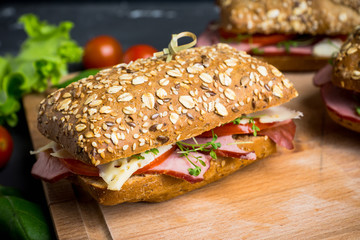 Sandwich with cereal bread, ham, tomatoes and cress on the dark background. Selective focus. 