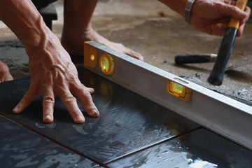 Ceramic Tiles. Tiler placing ceramic wall tile in position over adhesive with lash tile leveling...