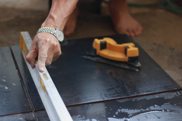 Ceramic Tiles. Tiler placing ceramic wall tile in position over adhesive with lash tile leveling system