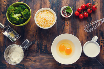 Ingredients for broccoli and tomatoes quiche cooking. Wooden rustic table, top view.
