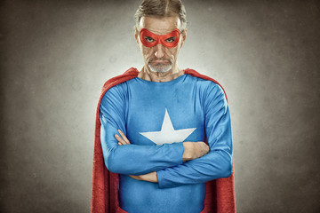 senior superhero man in blue costume red cloak and mask old portrait on textured background © ZoneCreative