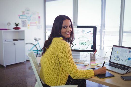 Smiling female graphic designer working in creative office