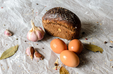 Still life of bread, eggs, garlic and spices.