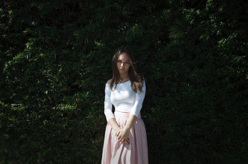 Beautiful young female with strong look in front of green tree wall