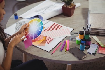 Businesswoman holding color swatch at office desk