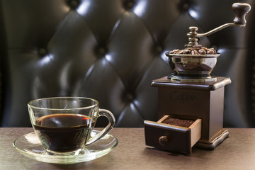 Old coffee grinder and coffee cup on wooden table