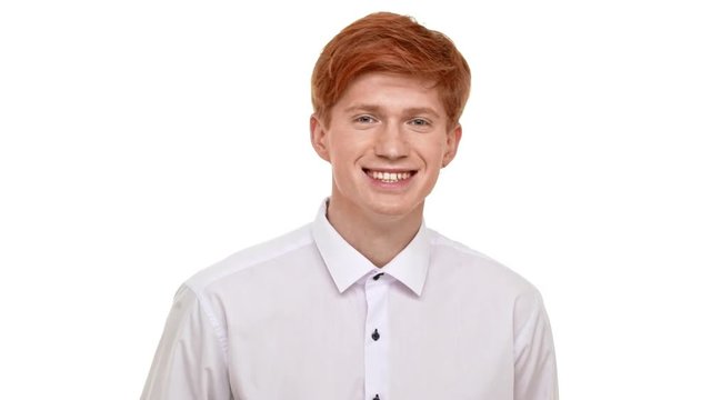 Young handsome Caucasian redhead man calmly standing on white background smiling laughing and showing ok in slowmotion