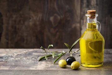 Gordijnen Virgin olive oil in a crystal bottle on wooden background.Copyspace   © chandlervid85