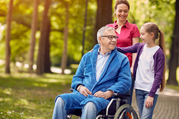 Happy wheelchair man with daughter and granddaughter.