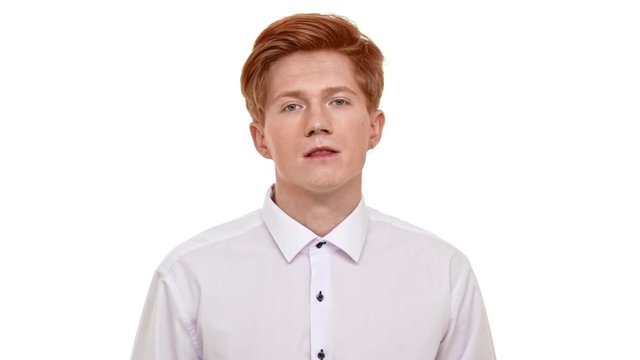 Young confident foxy Caucasian man straighten collar and doing hair up in front of camera on white background in slowmotion