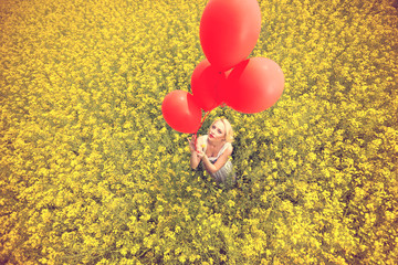 Woman with balloons in yellow field