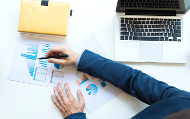 Business man working at office with laptop and documents on his desk. Analyze plans, papers, hands keyboard, business concept