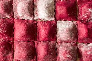 Preparing homemade pink ravioli (tortellini) with goat cheese on blue wooden table. Selective focus