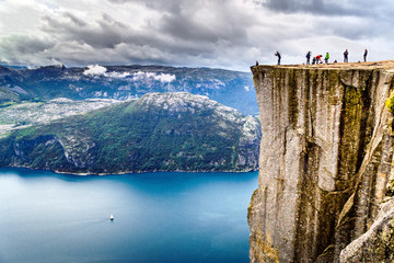 People hiking to Preikestolen, famous nature landmark in Norwey. Lysefjorden and mountains in background.