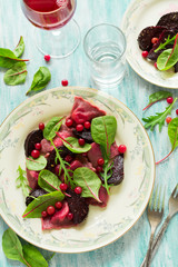 Homemade pink ravioli (tortellini) with goat cheese decorated beet leaves, beetroot slices and cranberry on wooden table. Selective focus