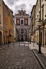 Fototapeta na wymiar The cobbled street and the facade of the baroque church in Poznan.