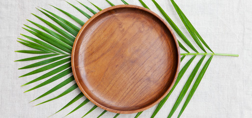 Wooden plate with palm leaf. Copy space. Top view.