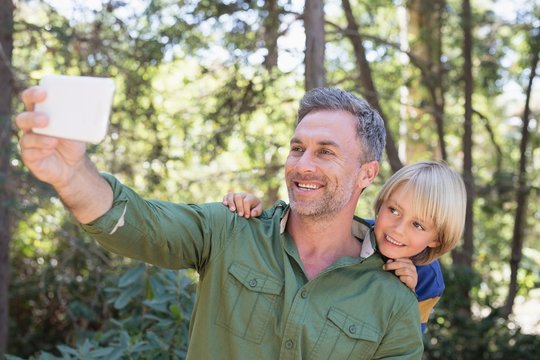 Smiling father and son taking selfie in forest