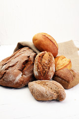 Different kinds of bread and bread rolls on board from above. Ki