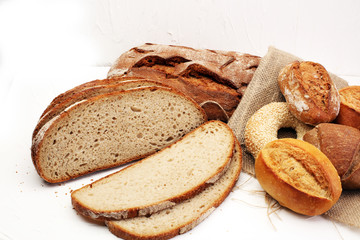 Different kinds of bread and bread rolls on board from above. Kitchen or bakery poster design.