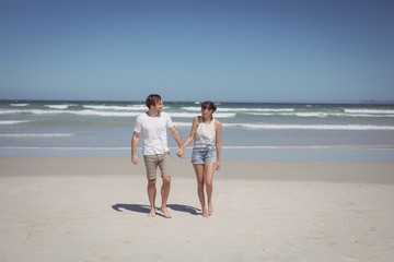 Fototapeta na wymiar Full length of couple holding hands at beach