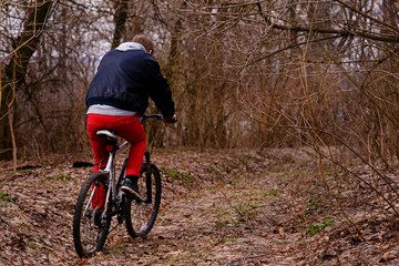 Obraz premium young man with backpack riding bicycle on mountain road in the forest