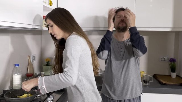 Man very angry with wife in kitchen making funny crazy faces