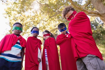 Friends in superhero costumes standing at campsite