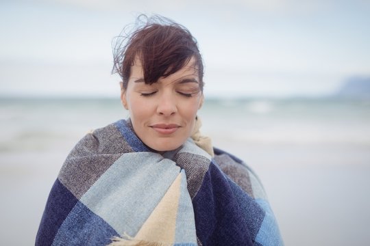 Young woman with eays closed wrapped in blanket during winter