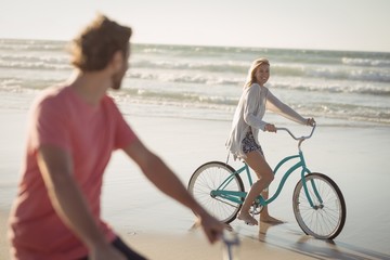 Couple riding bicycle at beach