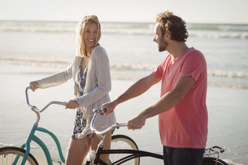 Obraz premium Happy young couple with bicycles at beach