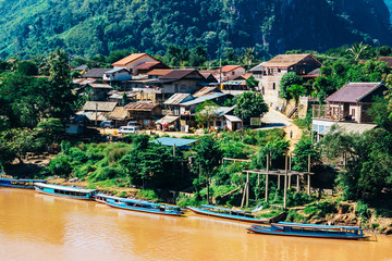 Naklejka premium Colorful landscape of Nong Khiaw and orange-yellow muddy Ou river with local boats, Laos