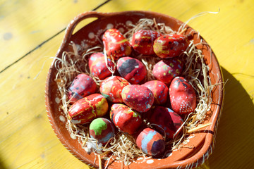 Colorful Easter eggs on ceramic plate wooden table background. Many seasonal traditional religious handmade decoration