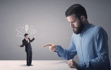 Young businessman fighting with miniature businessman