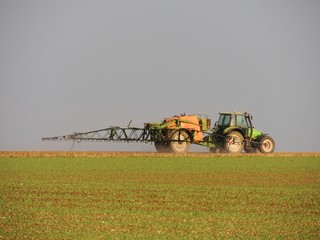 Tracteur pulvérisant des pesticides dans un champ.