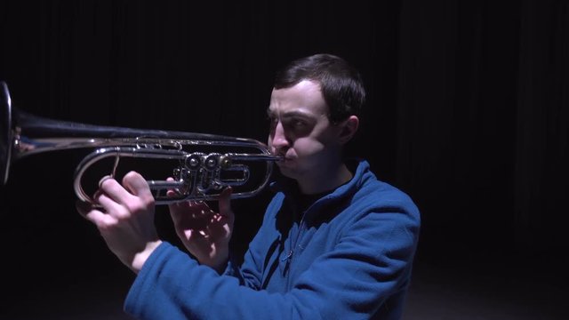 A musician plays the trumpet, isolated black background