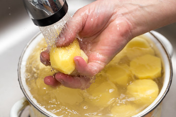 The cook washes the peeled potatoes in the water